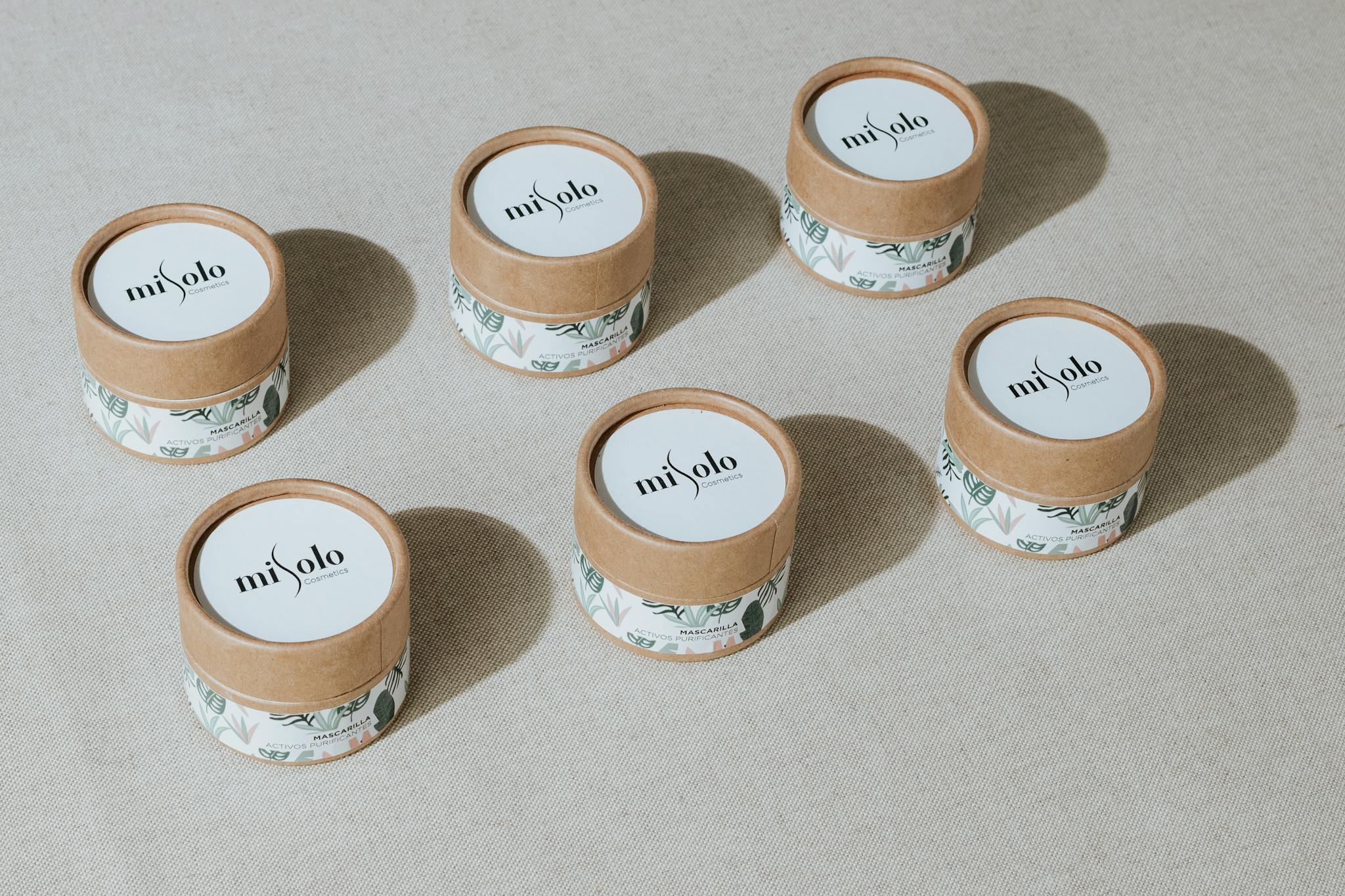 Six eco-friendly cosmetic containers arranged for a minimalist product display.